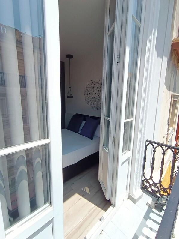 A narrow balcony with a bed and a hanging light fixture.