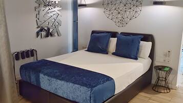 A modern bedroom with a wooden ceiling, a bed with a blue bedspread, two blue pillows, and geometric wall art.