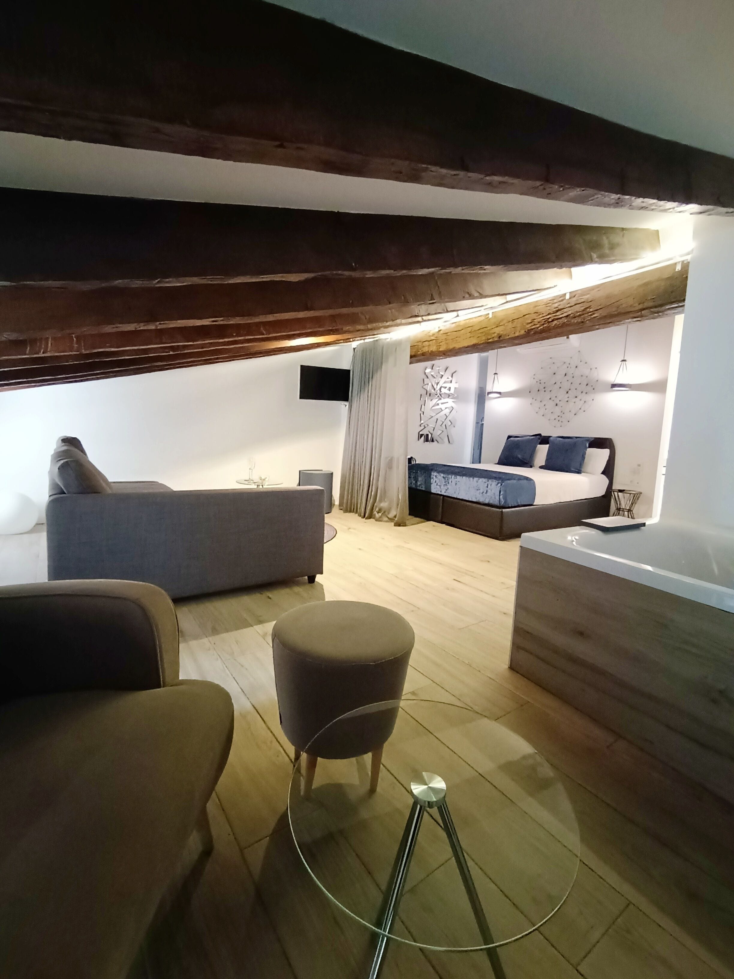 Un salon moderne avec un canapé, un pouf et une table basse en verre.