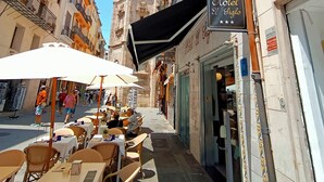 Una calle con mesas al aire libre, una torre del reloj y el letrero de un hotel.