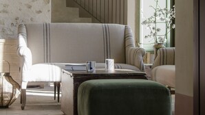 A living room with a sofa, ottoman, and a staircase. - Fontes Episcopi (Aragona)