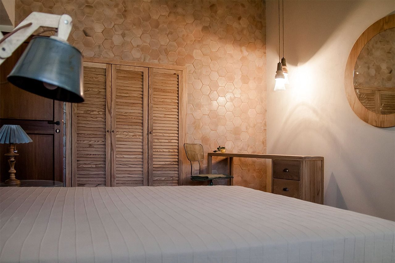 Un dormitorio con cama, una mesita de noche de madera, un escritorio, una silla y un armario.