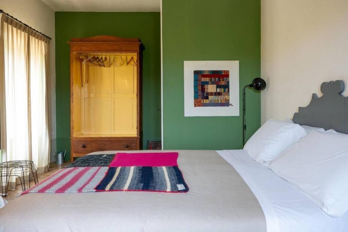 Un dormitorio con cama, un armario de madera, una pared verde y un cuadro enmarcado.