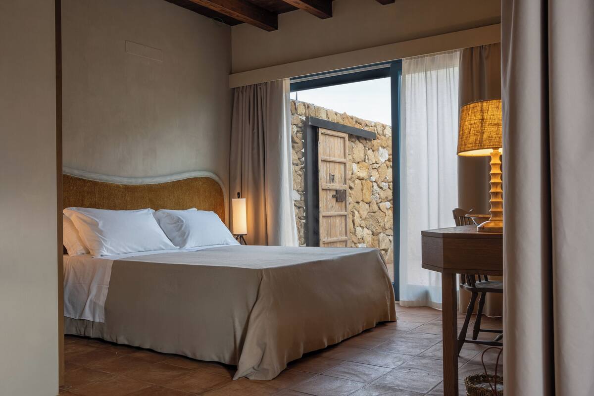 Un dormitorio con cama, escritorio y pared de piedra.