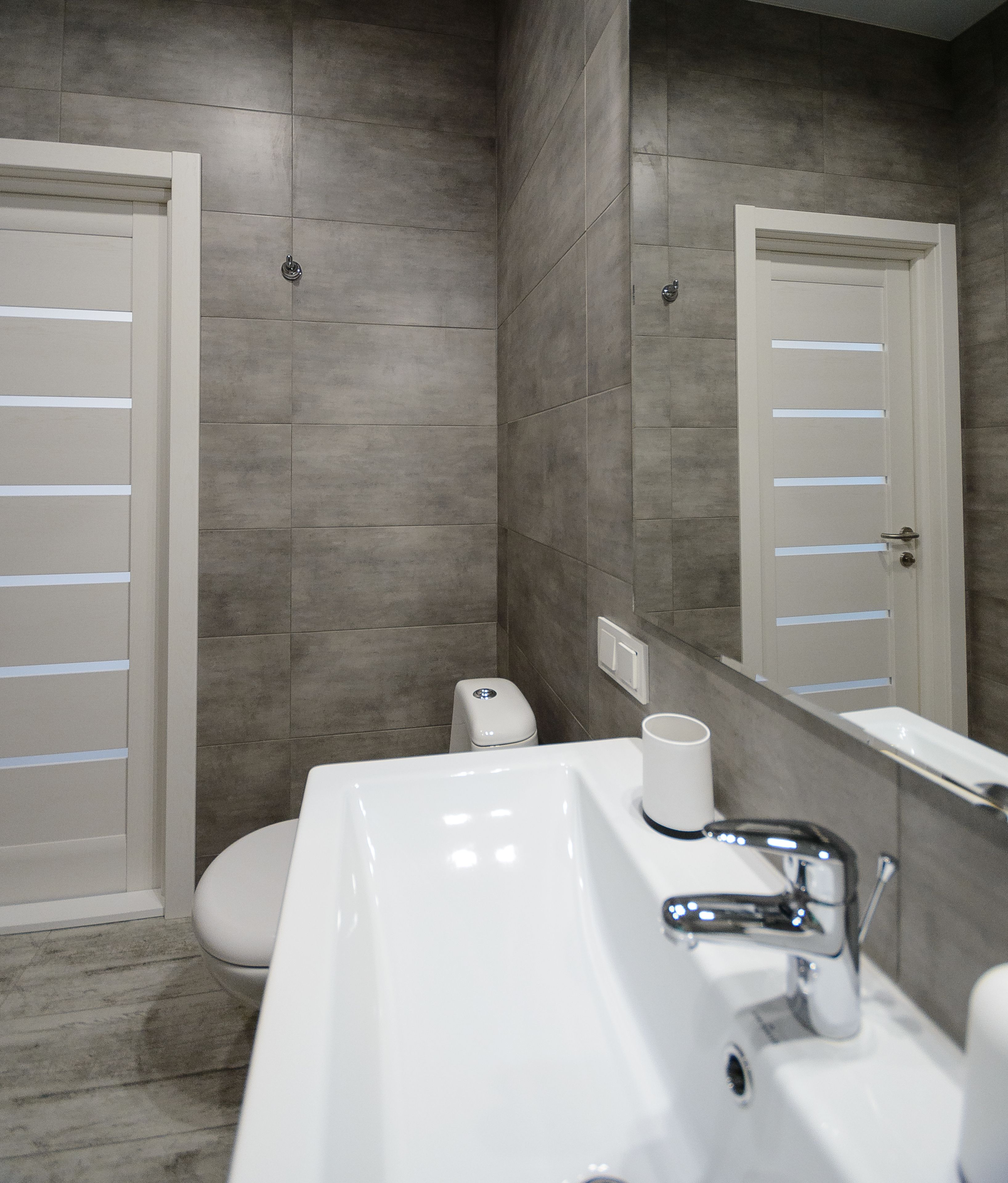 Een moderne badkamer met een witte wastafel, spiegel en toilet.