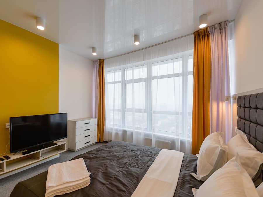 A hotel room with a bed, a television, a dresser, and a window with curtains.