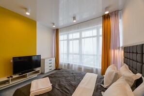 A hotel room with a bed, a television, a dresser, and a window with curtains. - Partner Guest House Klovskyi (Kyiv)