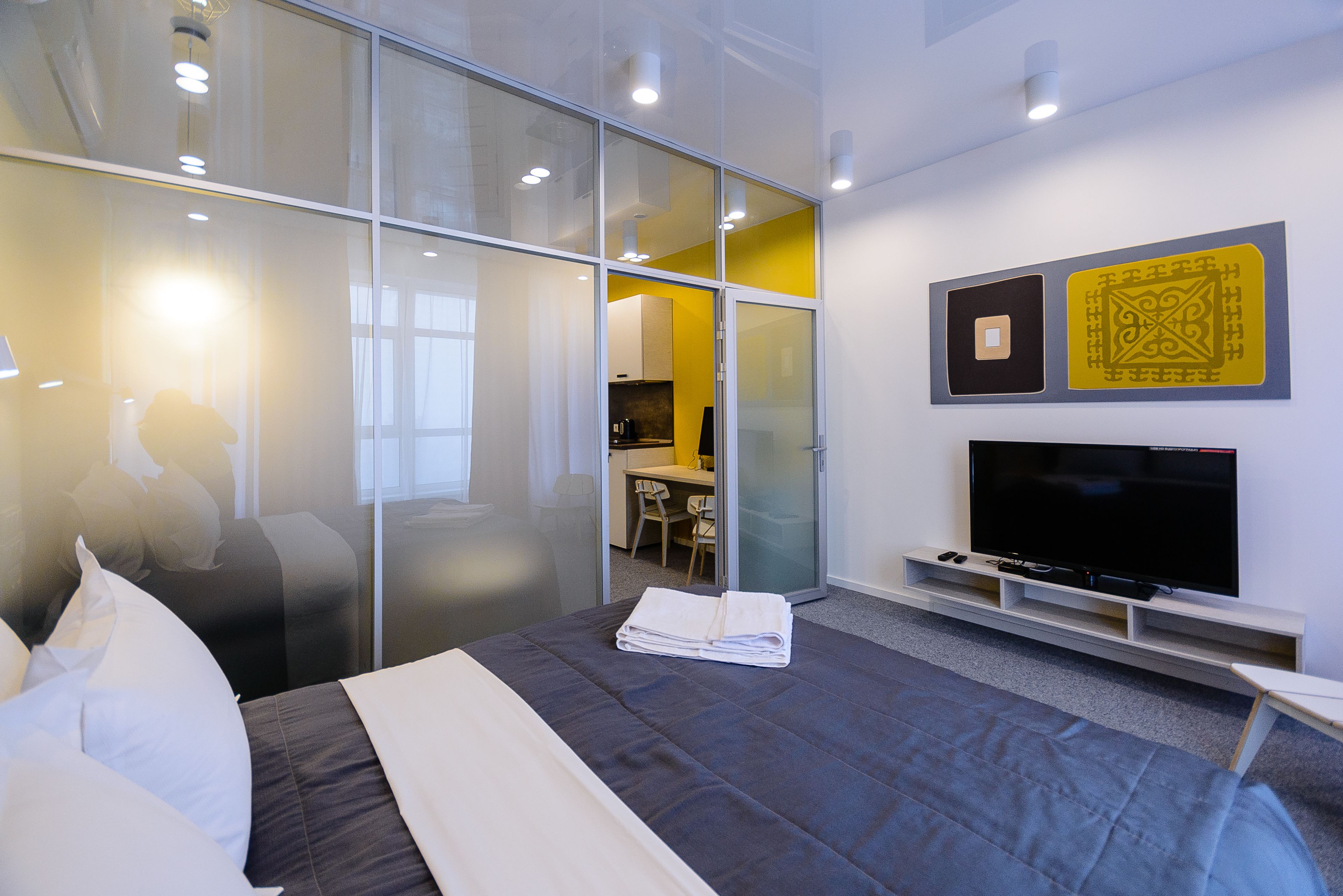 A modern hotel room with a bed, a television, and a desk area.