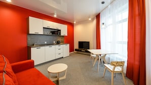 Un espacio habitable compacto con kitchenette, comedor, sofá y televisor.