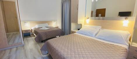 A hotel room with two beds, a large mirror, and bedside lamps.