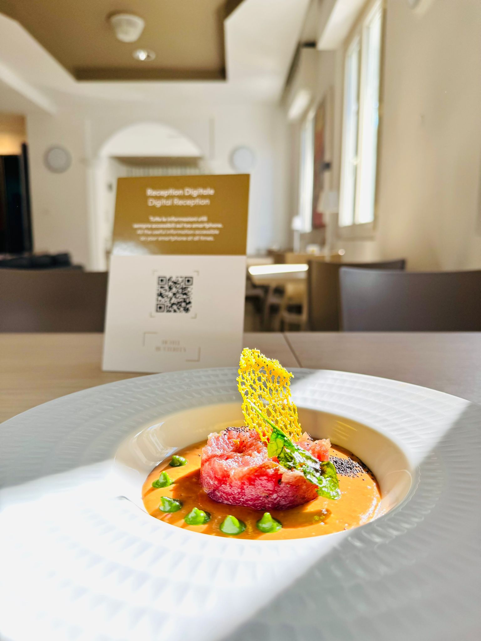Ein modernes Hotel-Interieur mit einer Rezeption, einem Schild mit einem QR-Code und einem Tisch mit einem angerichteten Gericht.