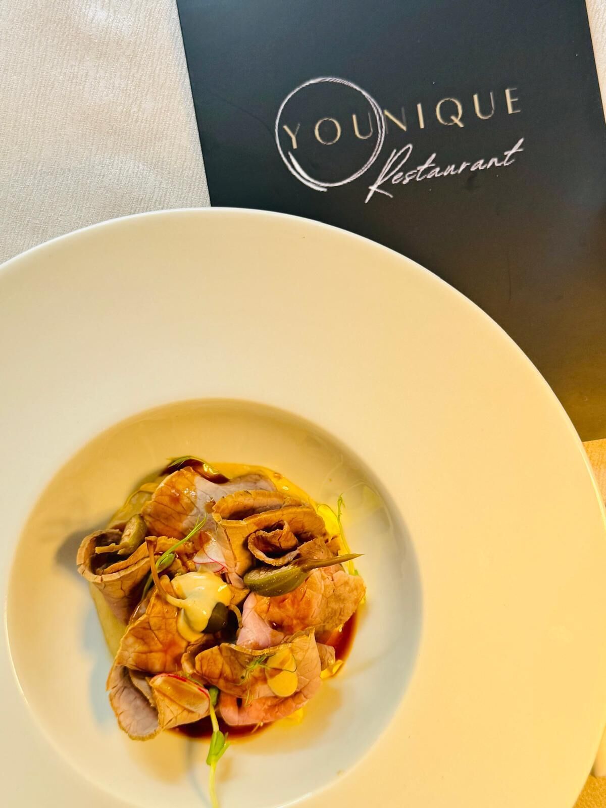 A plate of food with a unique presentation, placed on a table with a 'Unique Restaurant' sign in the background.