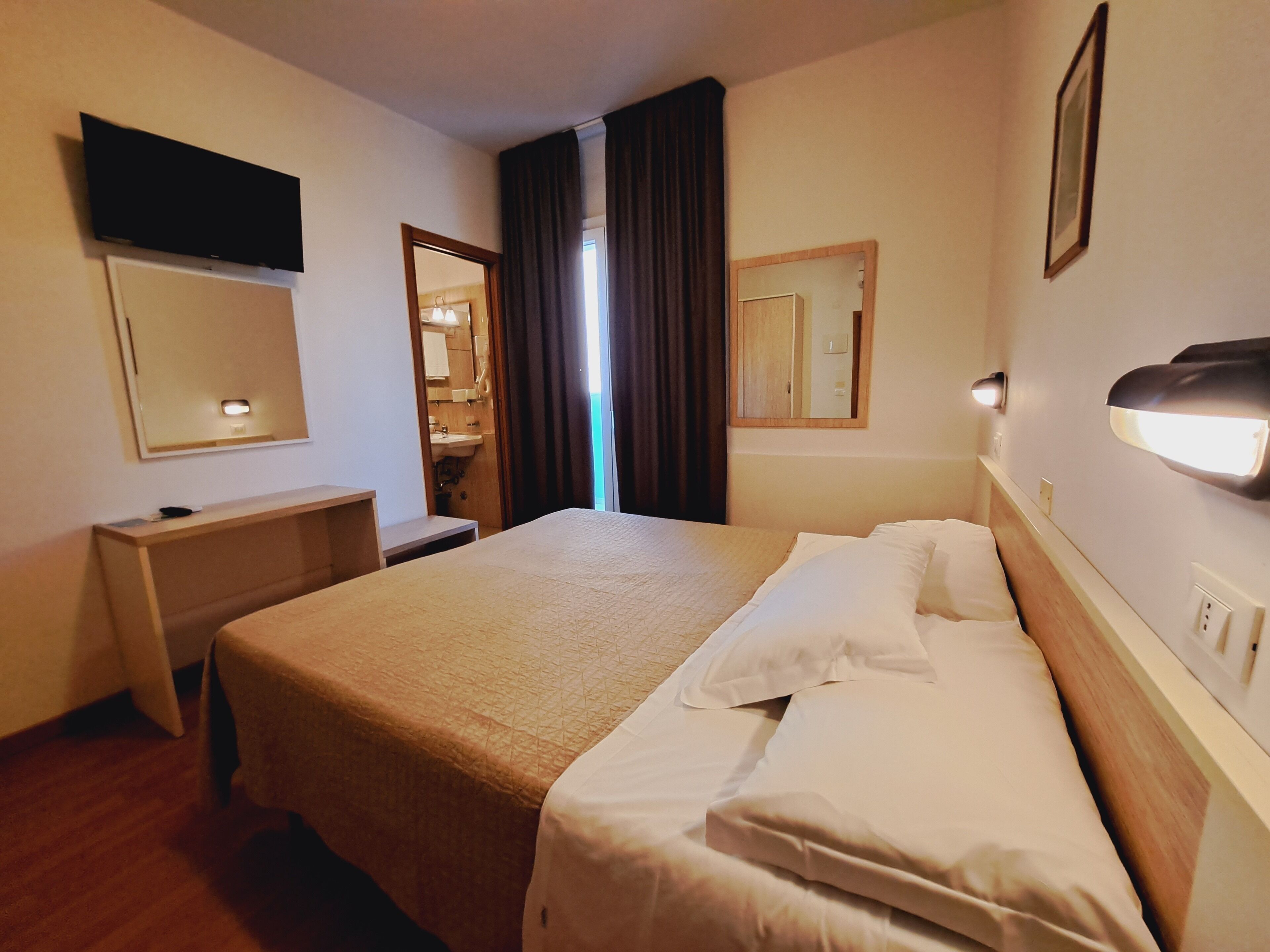 Une chambre d’hôtel équipée d’un lit, d’une table de chevet et d’un téléviseur fixé au mur.