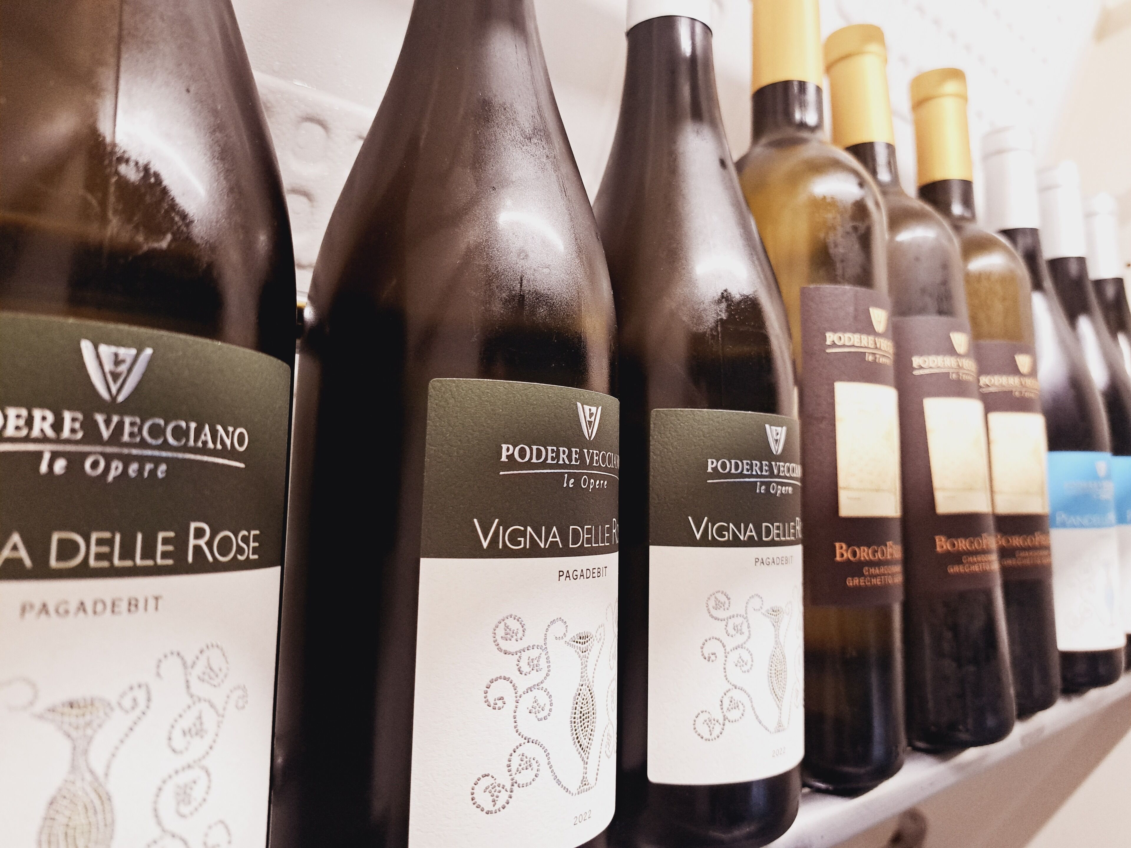 Una hilera de botellas de vino con etiquetas, incluyendo 