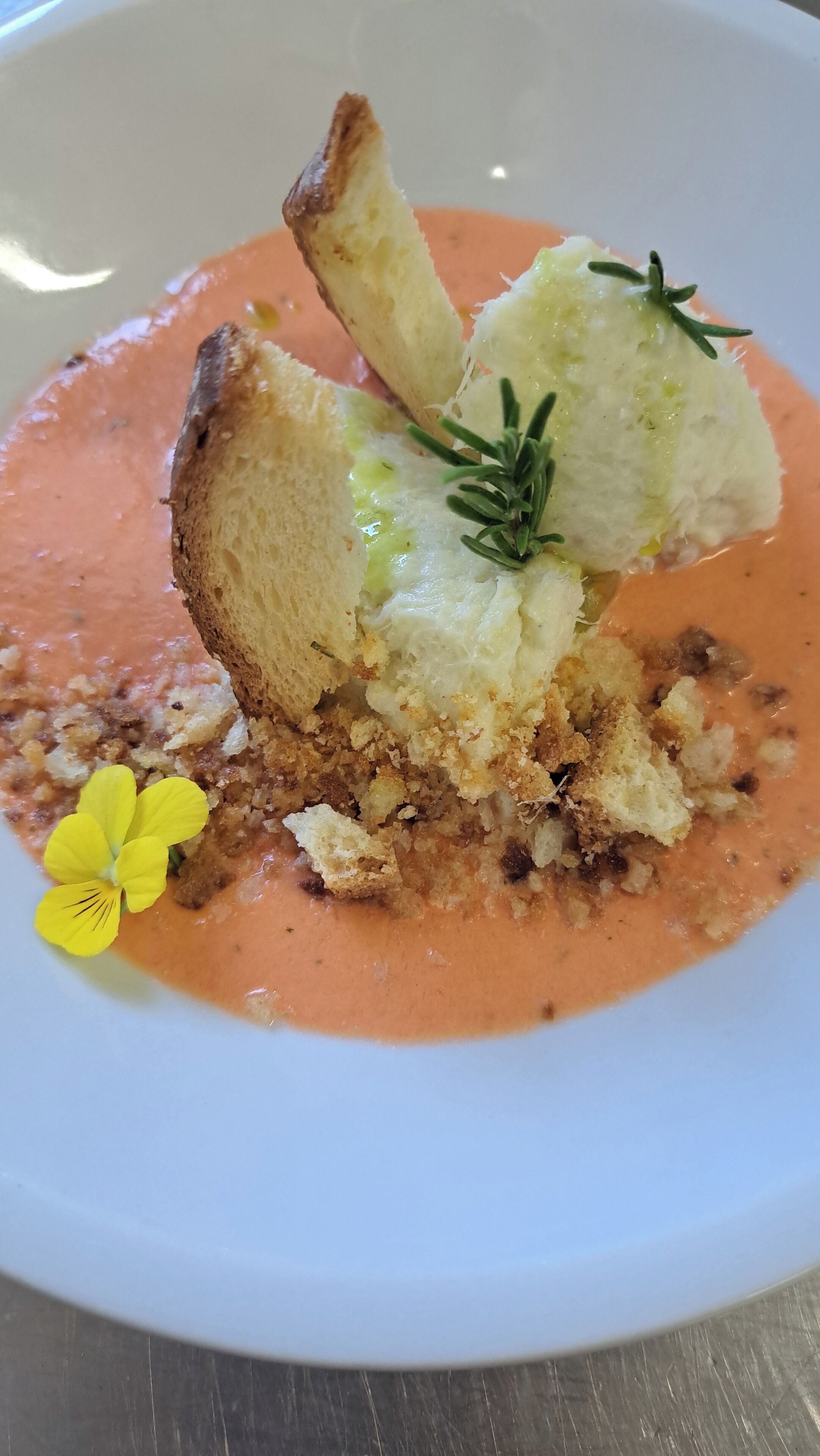 A dish with bread, cream, and a flower garnish on a plate.