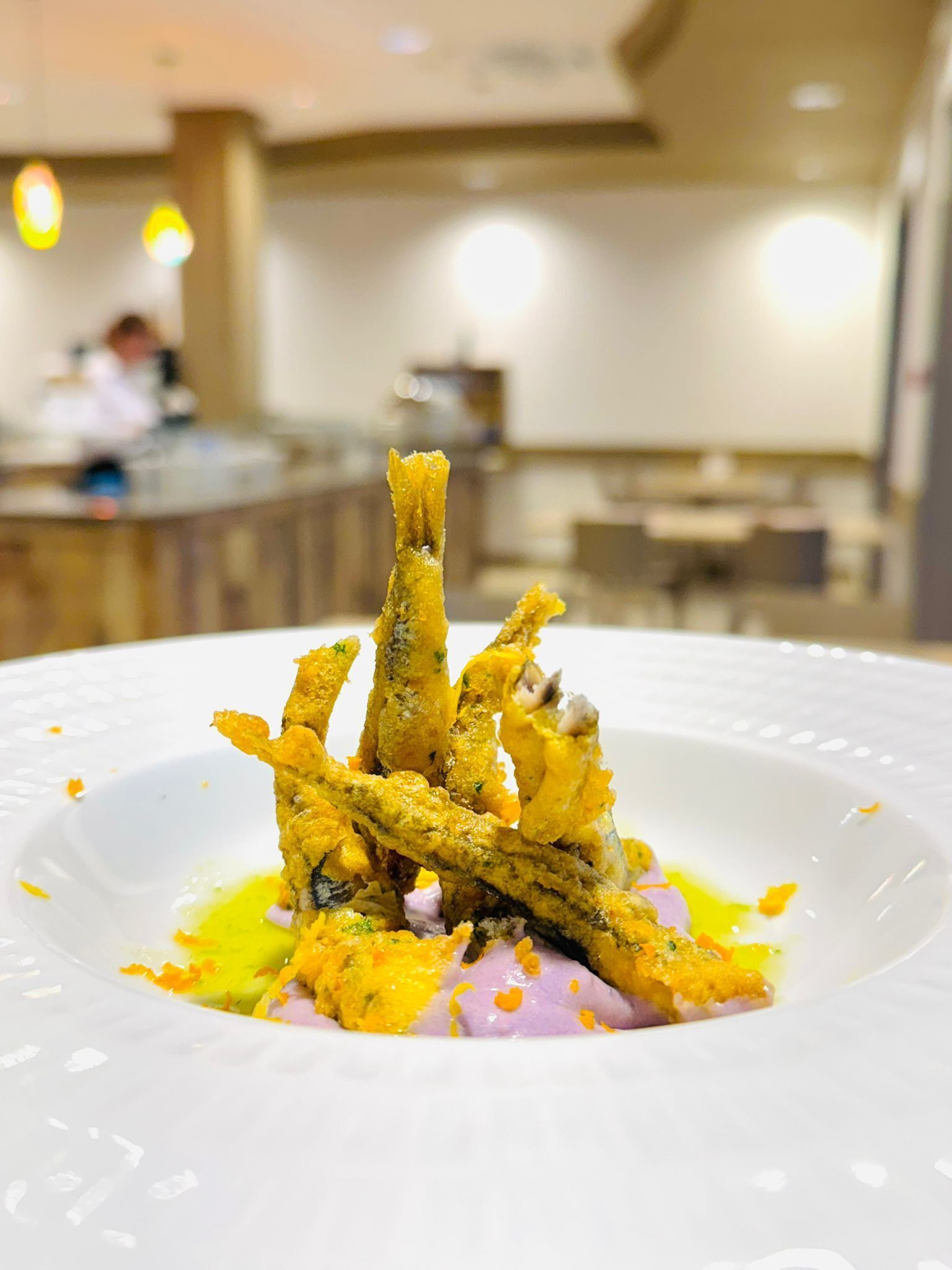 Un piatto bianco con un'insalata di pesce fritto e salsa gialla.