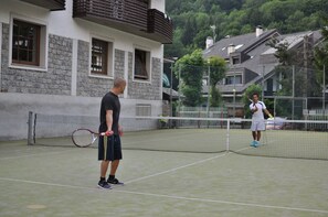 En tennisbane med et net i midten, omgivet af bygninger.