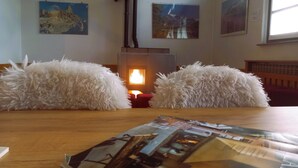 A room with a wooden table, two fluffy white cushions, a fireplace, and wall-mounted artwork. - Residence Biancaneve (Aprica)