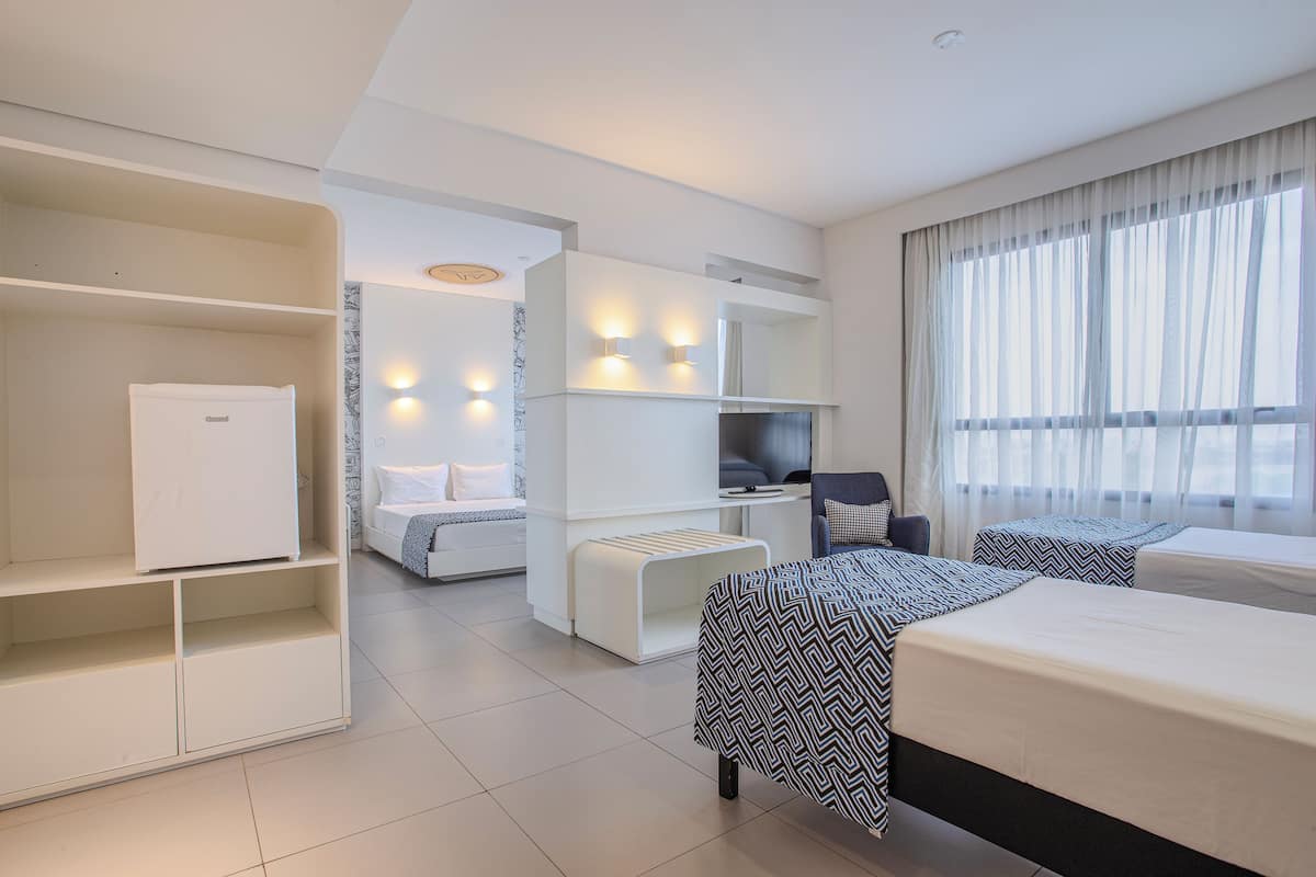Ein modernes Hotelzimmer mit Bett, Schreibtisch, Stuhl, Kleiderschrank und Fernseher.