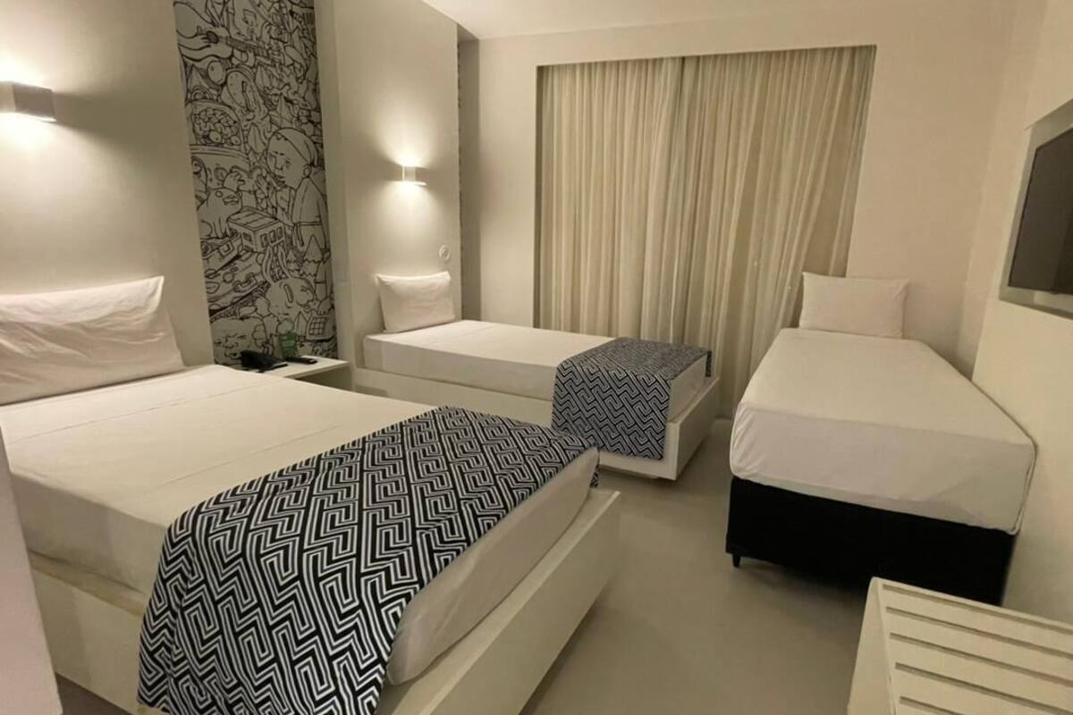 Ein Hotelzimmer mit zwei Betten, einem Schreibtisch, einem Stuhl, einem Fernseher und einem Vorhang.