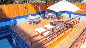 Una piscina al aire libre, sombrillas, sillones reclinables de piscina