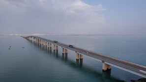 Un puente largo sobre aguas tranquilas, con el perfil urbano de una ciudad a lo lejos.
