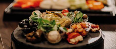 A variety of food items on a round serving tray, including olives, nuts, and vegetables.