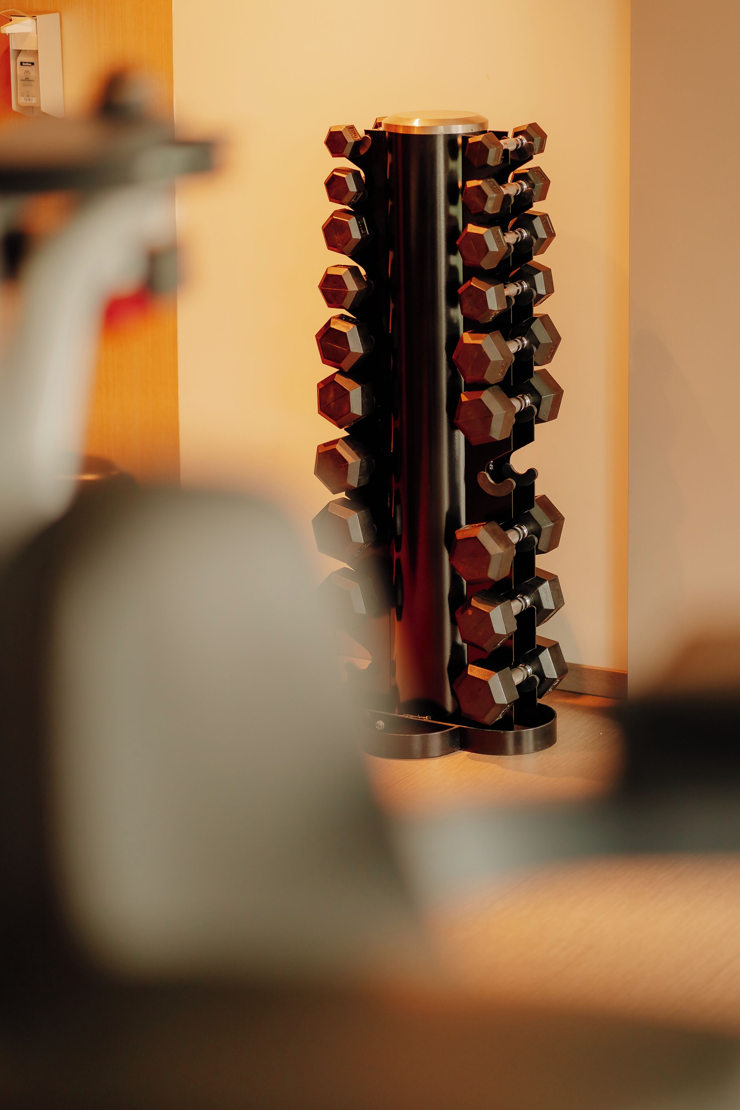 A metallic, hexagonal dumbbell rack with weights.