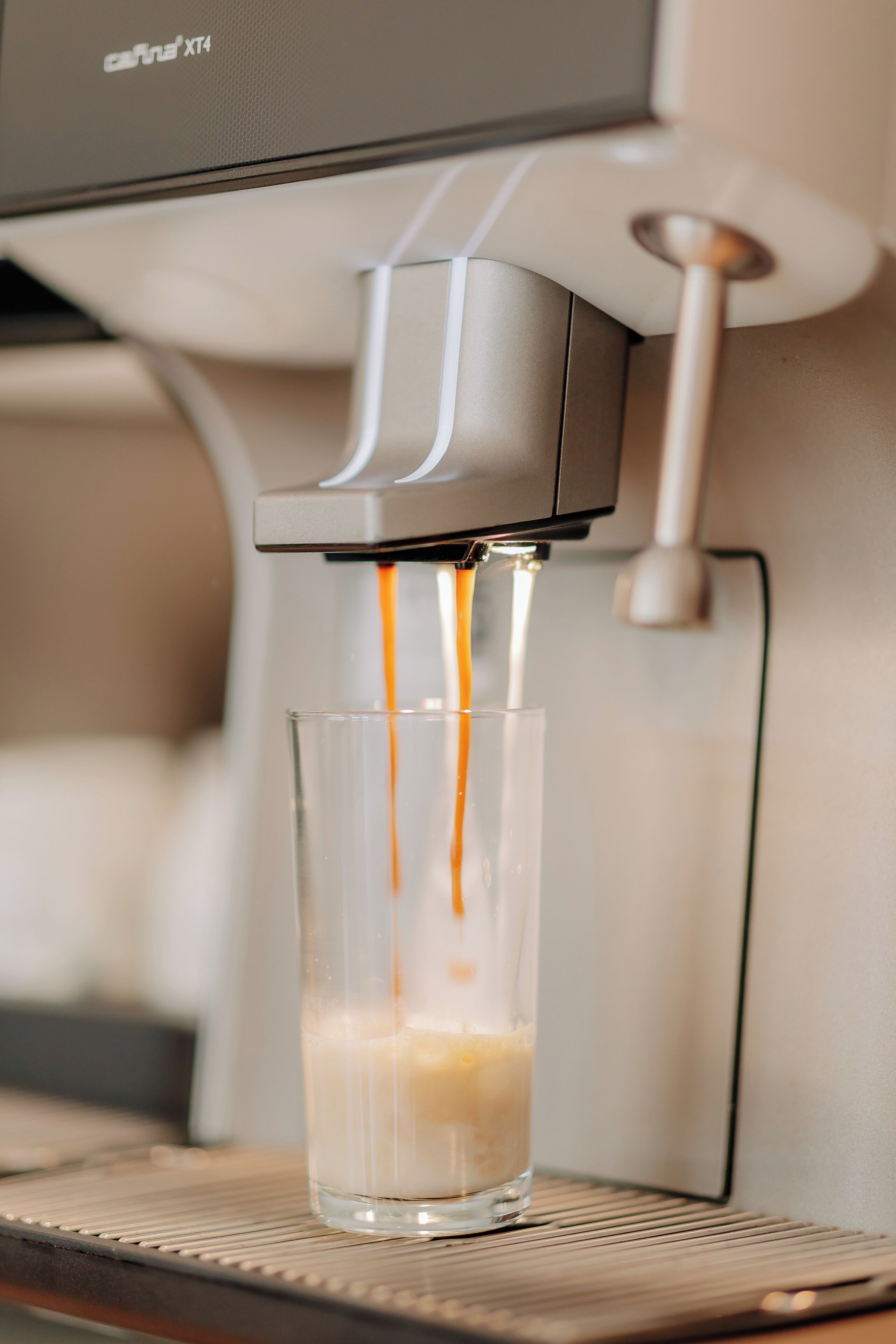 A coffee machine dispensing espresso into a glass.