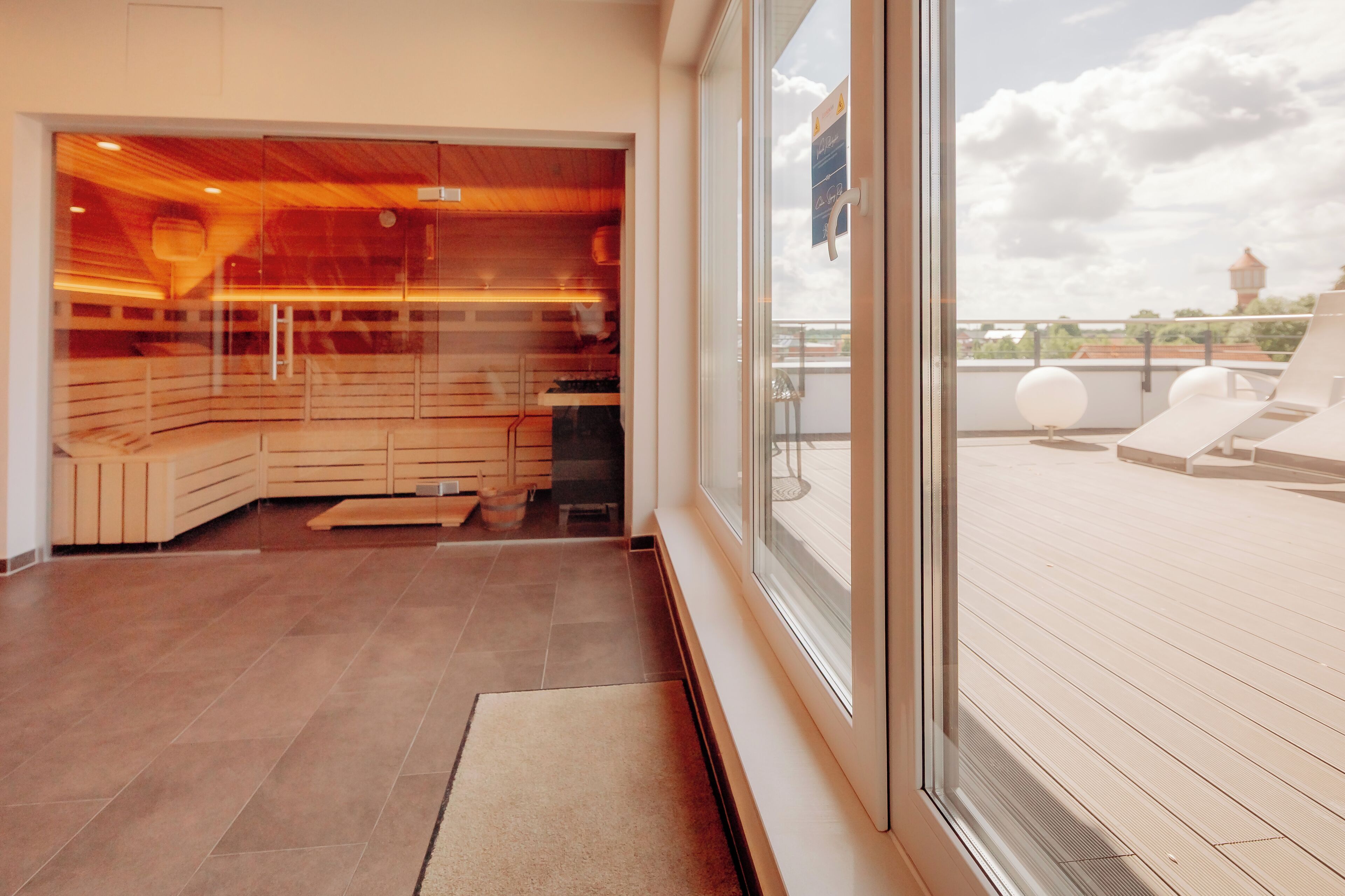 A modern spa room with a wooden ceiling, a glass wall, and a view of the deck.