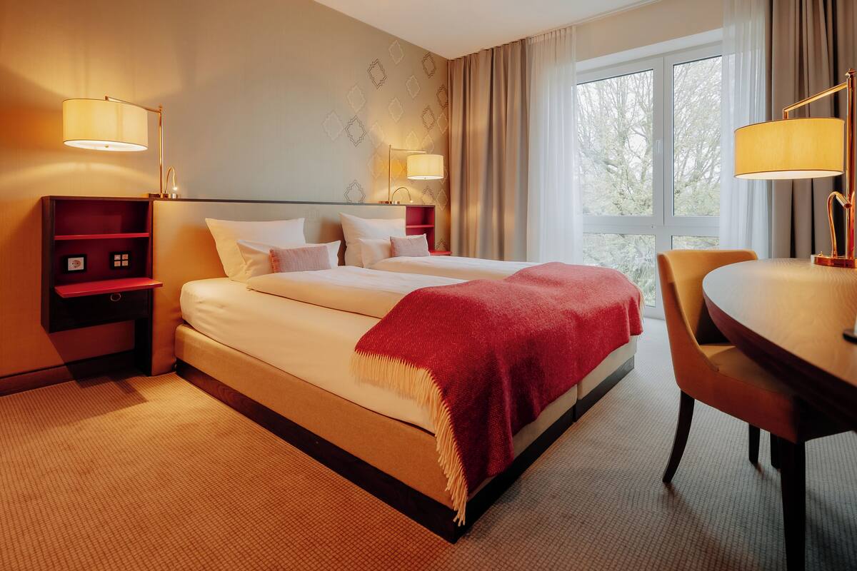 A hotel room with a large bed, two bedside tables, a desk, and a chair.