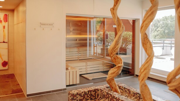 A spa area with wooden benches, a glass wall, and a sign reading 'FINNISCHE SAUNA'. - LOOKEN INN Lingen by Hackmann (Lingen)