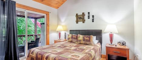 A bedroom with a large bed, wooden headboard, two bedside tables with lamps, and a view of the outdoors through a sliding door.