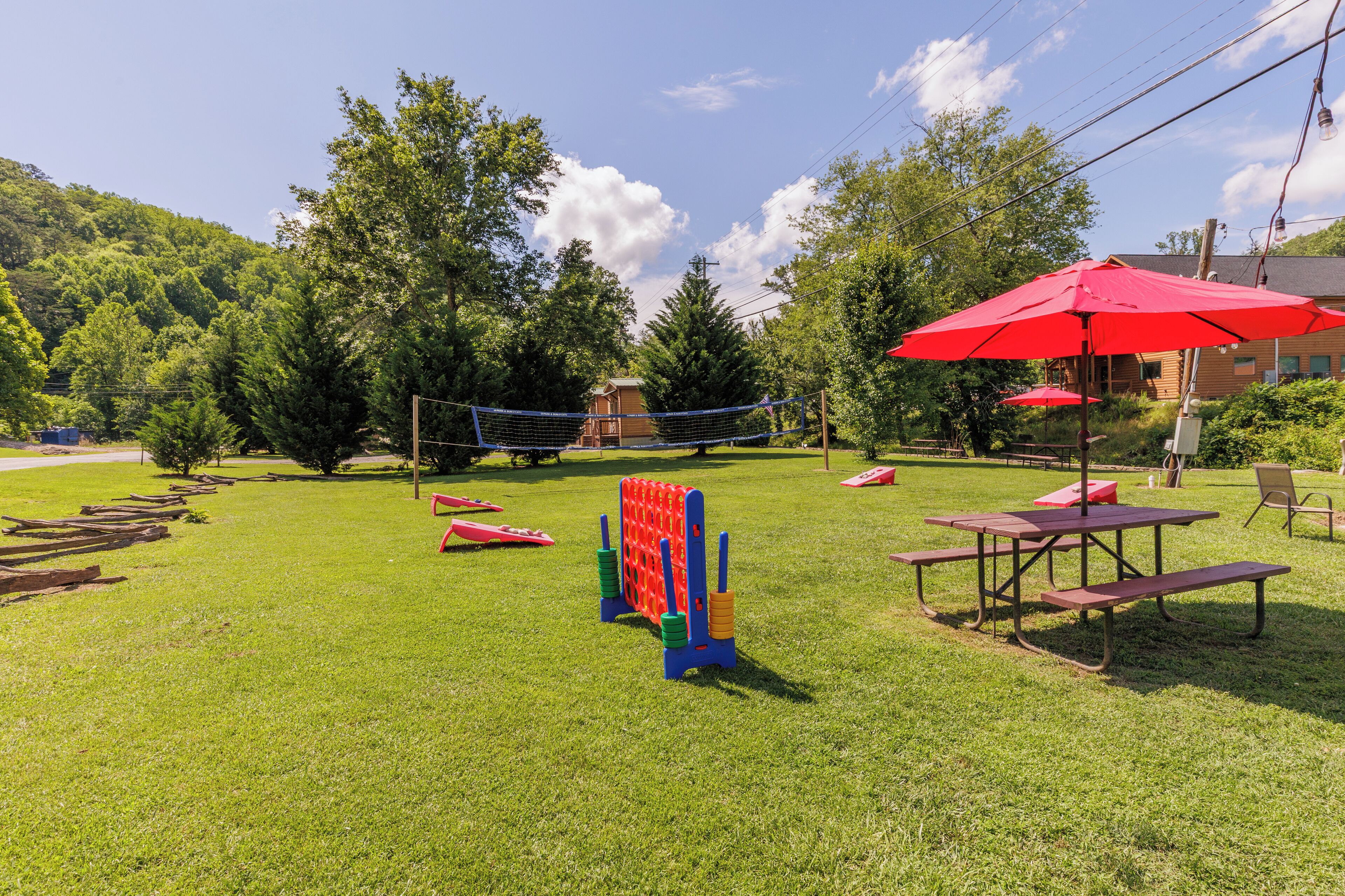 A grassy outdoor area with picnic tables and a volleyball net.