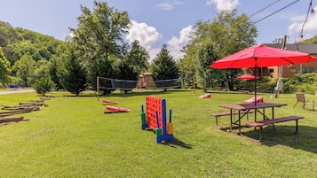 A grassy outdoor area with picnic tables and a volleyball net.