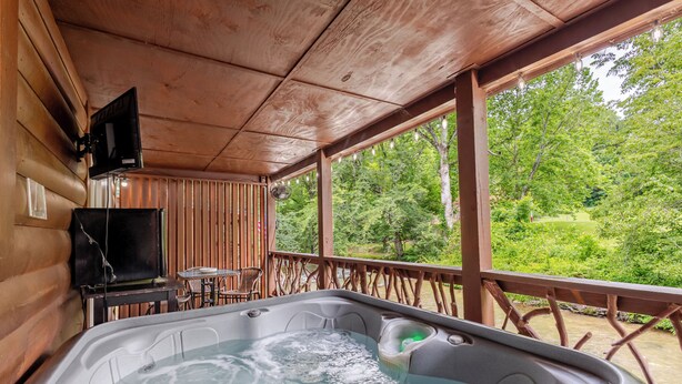 Een hottub met een houten terras en een televisie aan de muur.