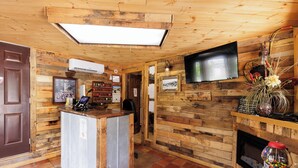 Een houten interieur met een receptiebalie, een televisie, een open haard en een koffieapparaat.