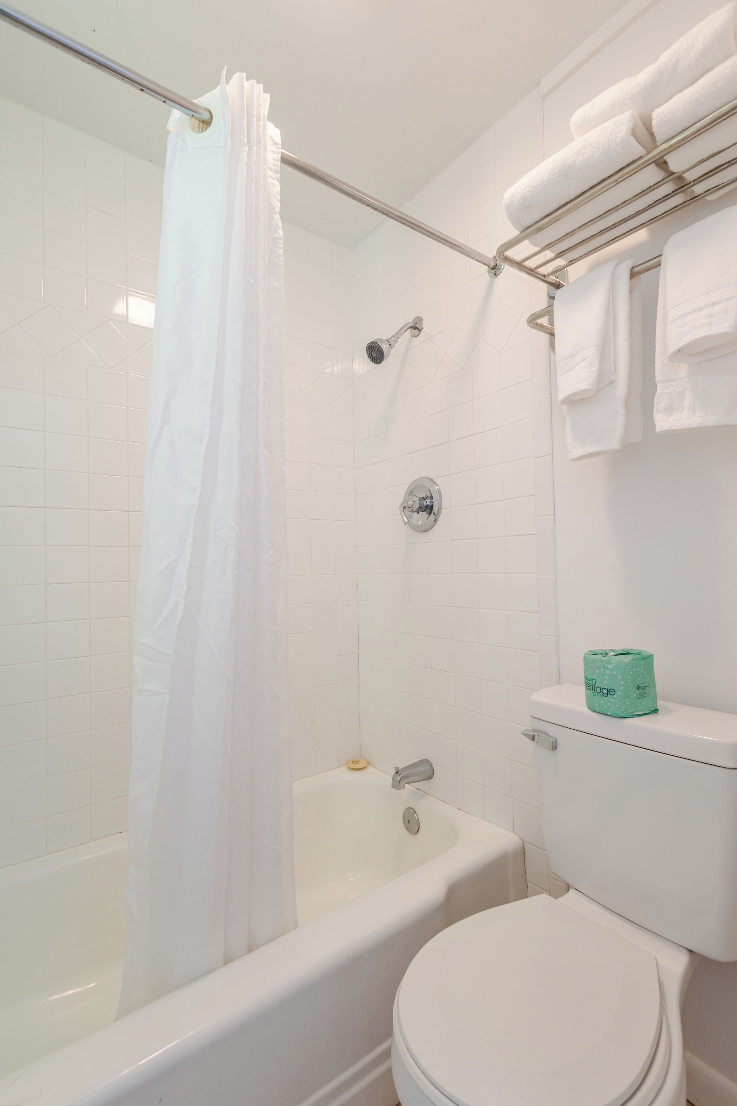 A bathroom with a bathtub, toilet, and shower curtain.