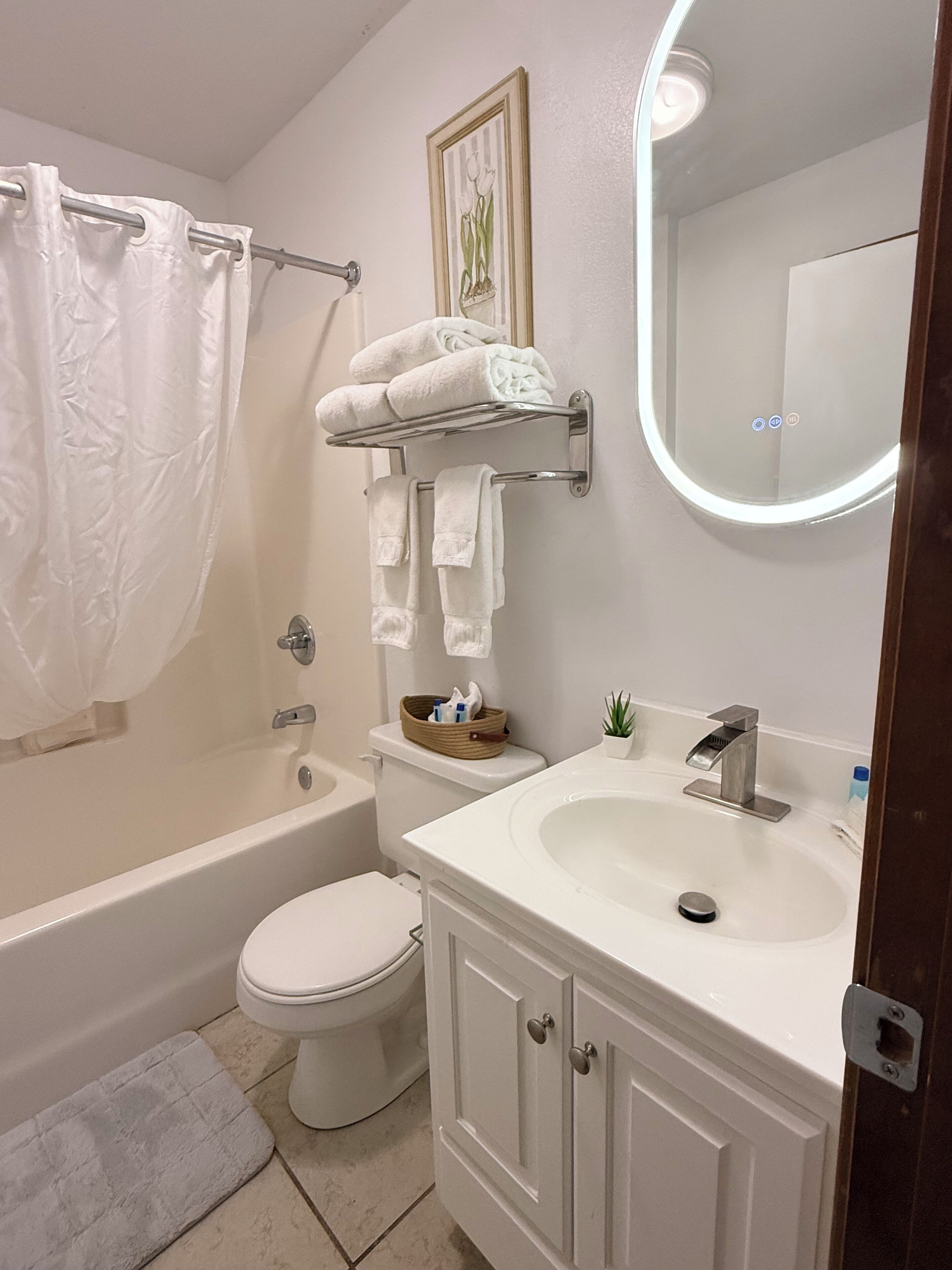 Un baño con bañera, inodoro, lavabo y toallero.
