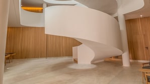 Un interior moderno con una escalera de caracol, techos altos y luz natural proveniente de tragaluces.
