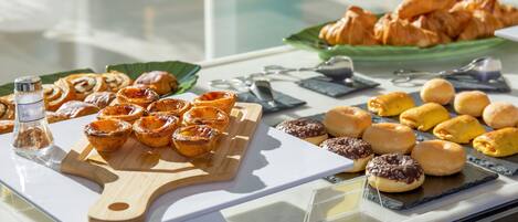 Verschiedene Gebäcke liegen auf einer Theke ausgestellt, darunter Törtchen, Croissants und Muffins.