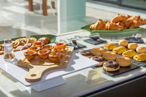A variety of pastries displayed on a counter, including tarts, croissants, and muffins.