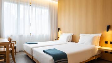 Habitación de hotel con dos camas, un escritorio y una silla.