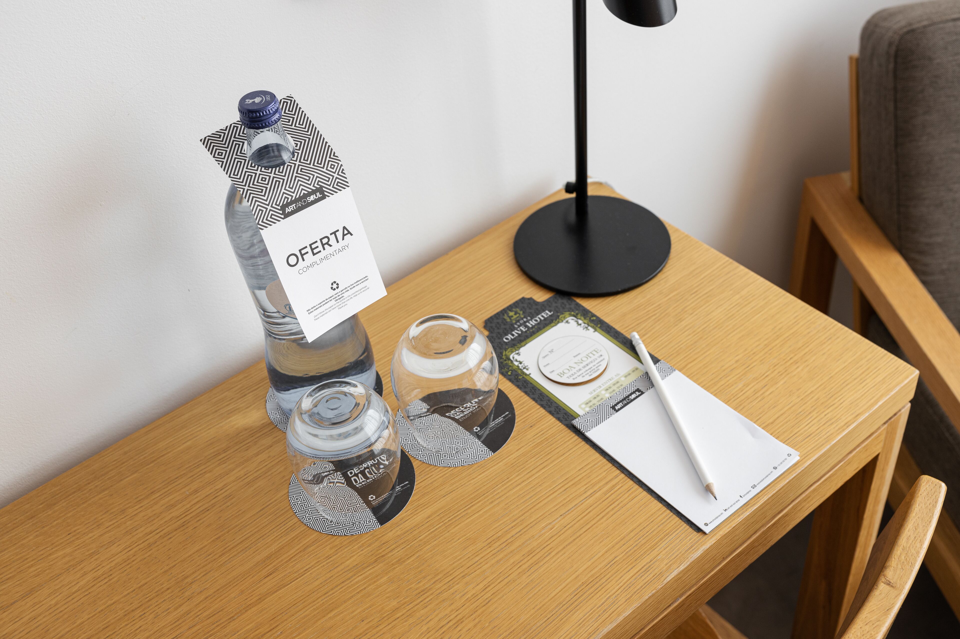 A wooden side table with a water bottle, a glass jar, a notebook, and a pen.