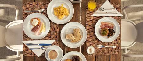 Una mesa de desayuno con platos de comida, cubiertos y una servilleta.