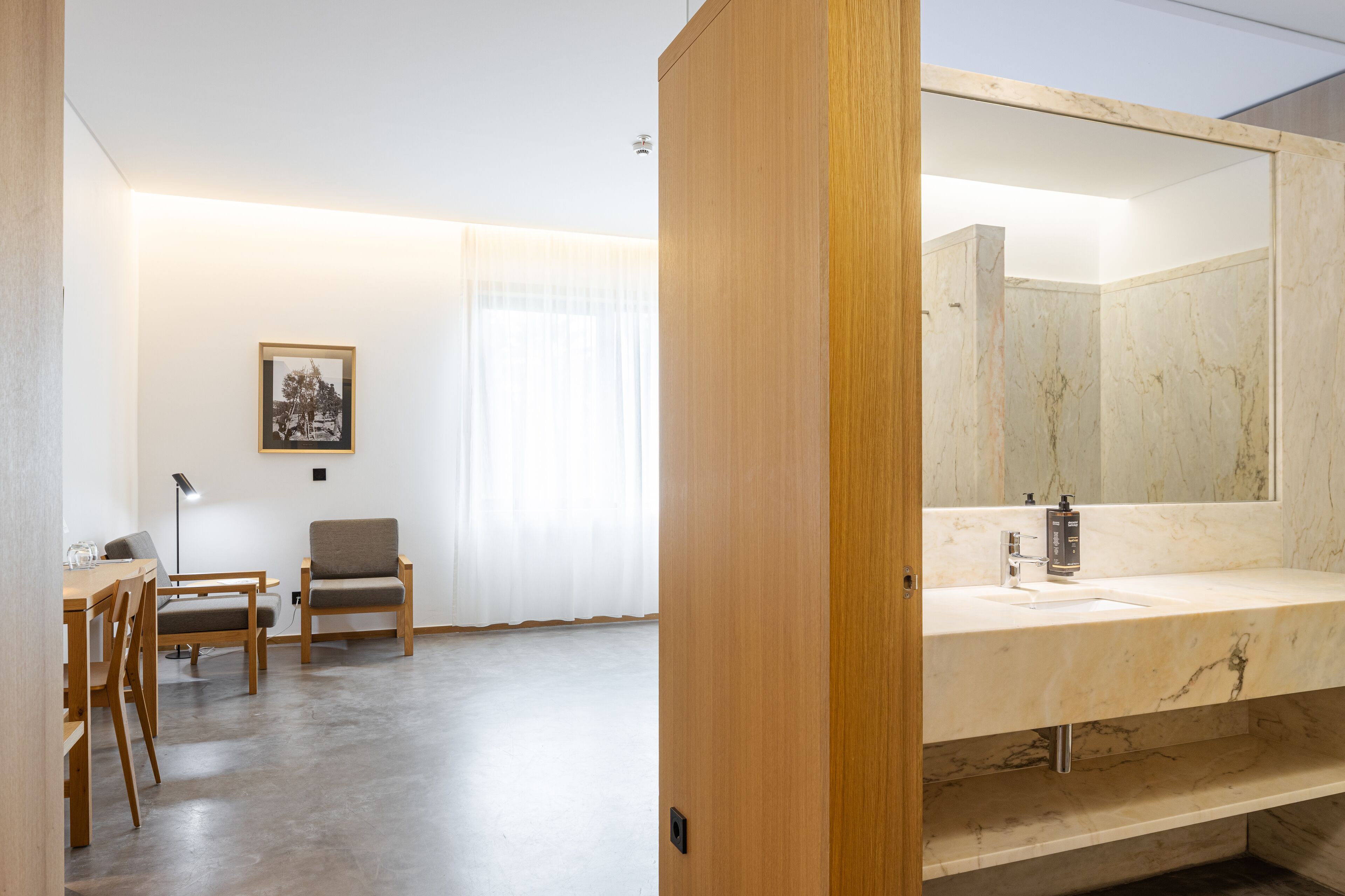 A modern bathroom with a large mirror, marble countertop, and a wooden door.