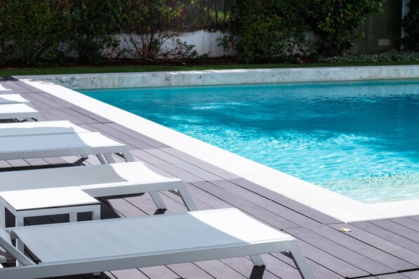 A swimming pool with white lounge chairs and a wooden deck.
