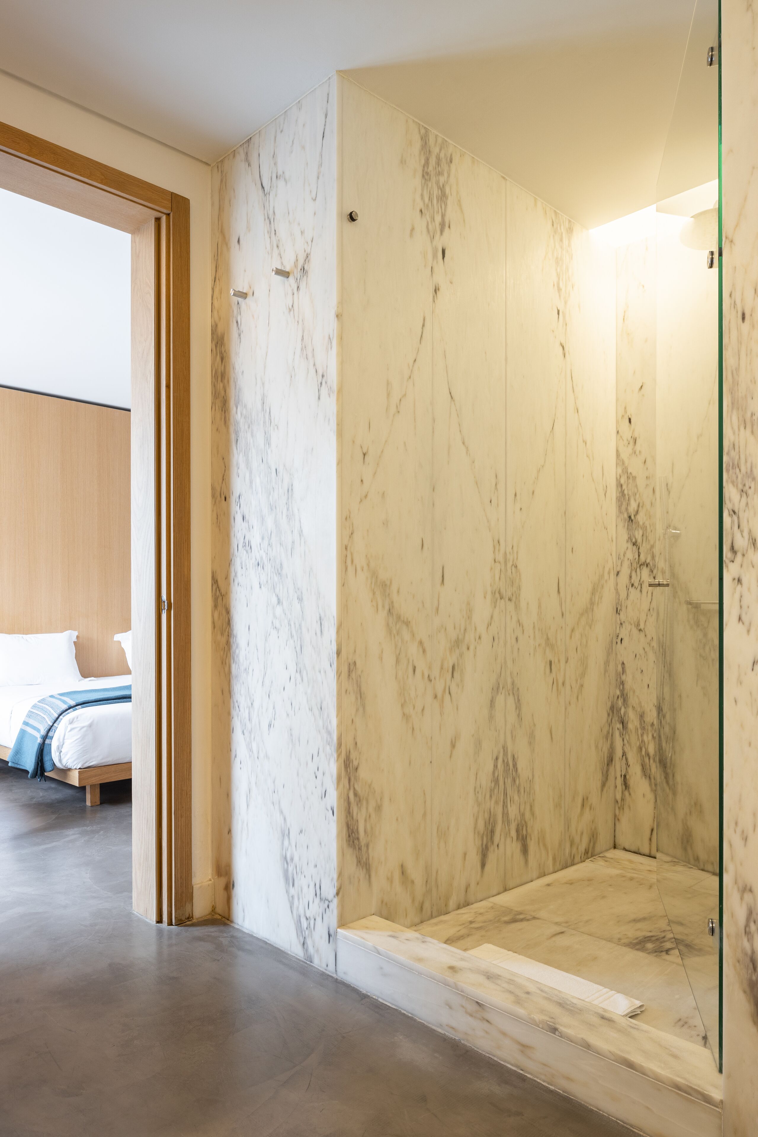 A modern bathroom with a glass shower enclosure and a marble wall.