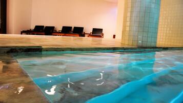 Una piscina con acqua cristallina, un muro piastrellato e diverse sedie a sdraio.