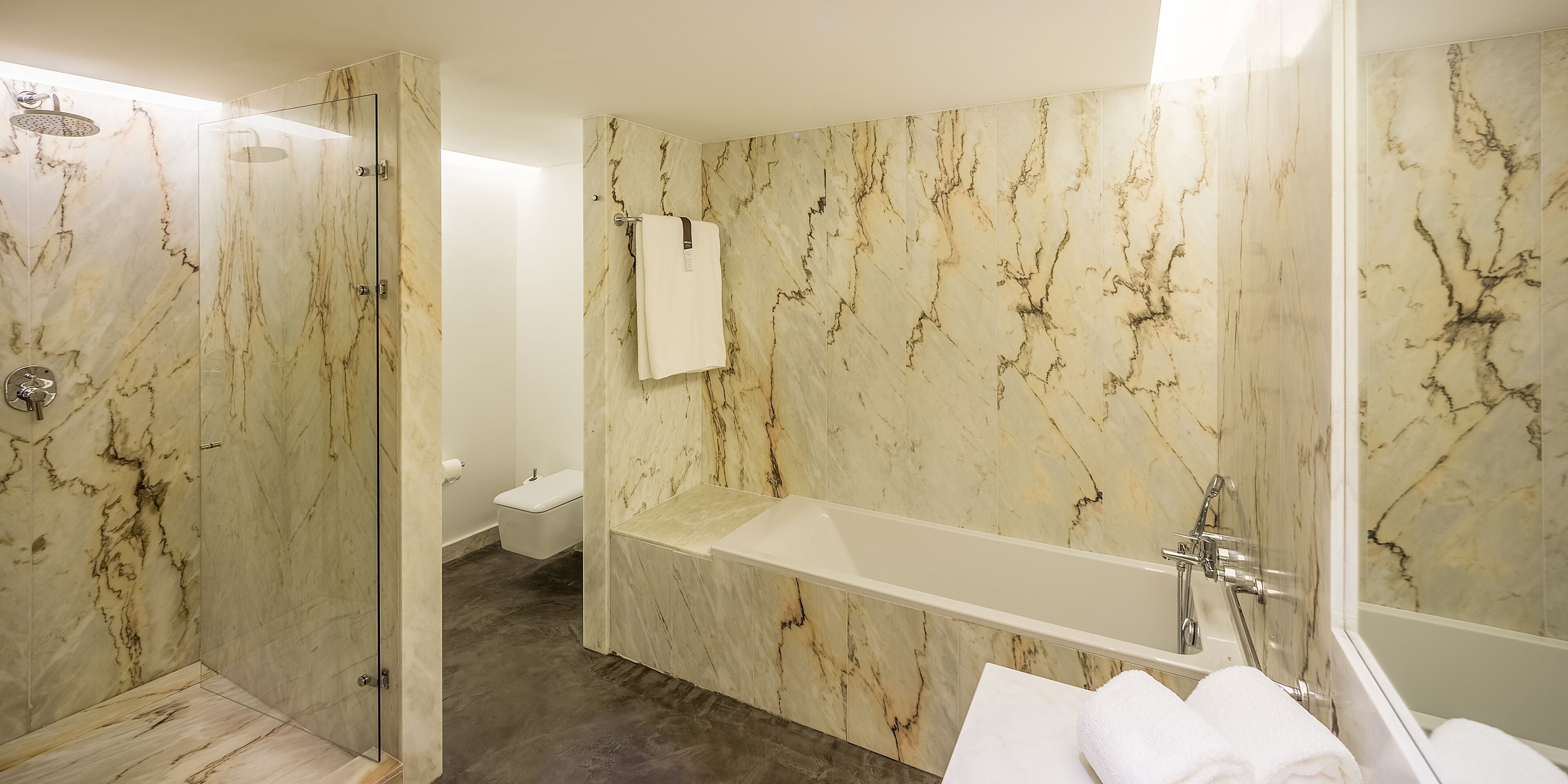 A bathroom with a glass-enclosed shower, a bathtub, and a toilet.